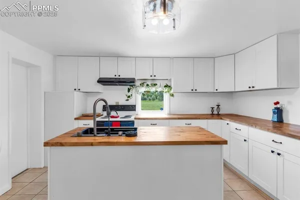 a kitchen with kitchen island granite countertop a sink a stove and white cabinets