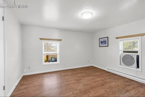 an empty room with wooden floor and windows