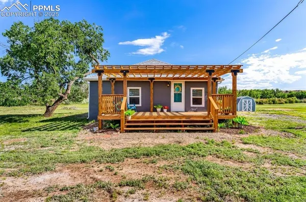 a view of a house with backyard wooden fence and a large tree