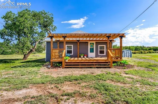 a view of a house with backyard wooden fence and a large tree