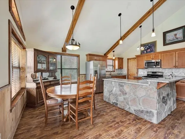 a dining room with stainless steel appliances kitchen island granite countertop a table and chairs with wooden floor