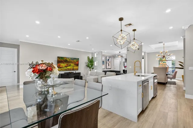 a kitchen with stainless steel appliances granite countertop a stove top oven a sink dishwasher and white cabinets with wooden floor