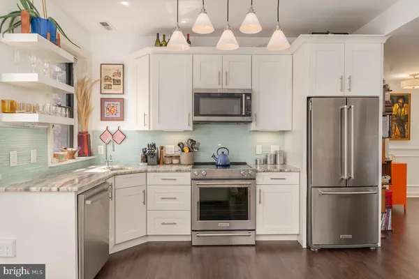 a kitchen with cabinets stainless steel appliances and wooden floor