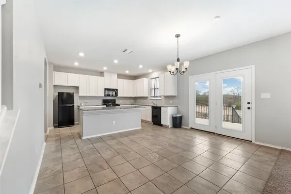 a large kitchen with kitchen island a stove a sink cabinets and a dining table