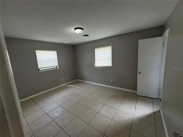 a view of an empty room with window and closet area