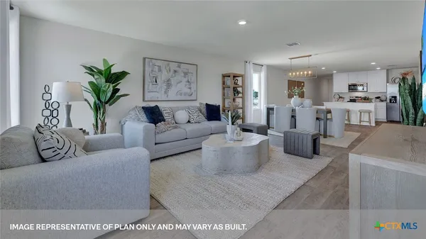 a living room with furniture a potted plant and kitchen view