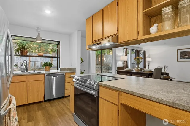 a kitchen with stainless steel appliances granite countertop a sink a stove and a wooden floors