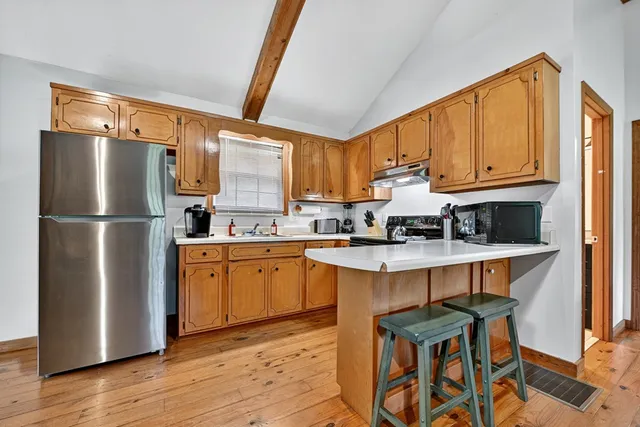 a kitchen with stainless steel appliances granite countertop a refrigerator a sink and white cabinets