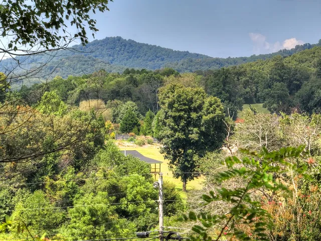 a kitchen with stainless steel appliances granite countertop a refrigerator a sink a stove and white cabinets with wooden floor