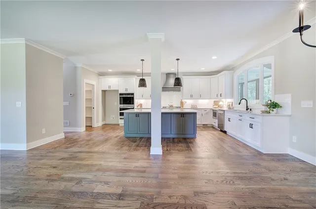 a kitchen with kitchen island white cabinets and wooden floor