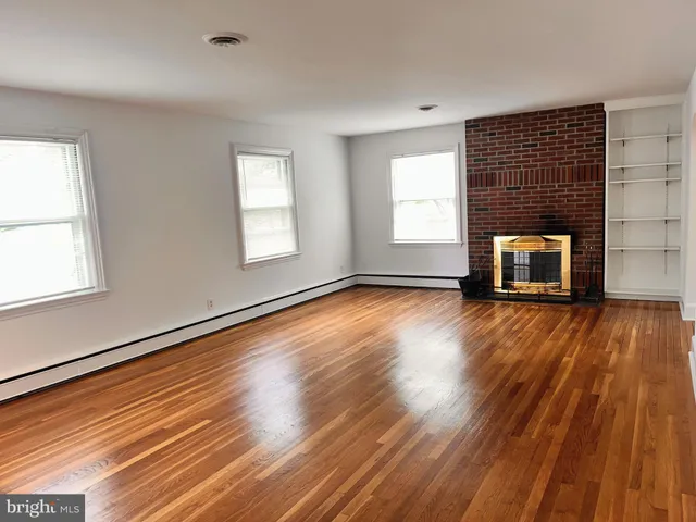an empty room with wooden floor windows and fireplace
