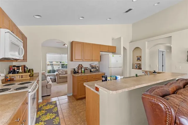 a living room with stainless steel appliances furniture and a kitchen view