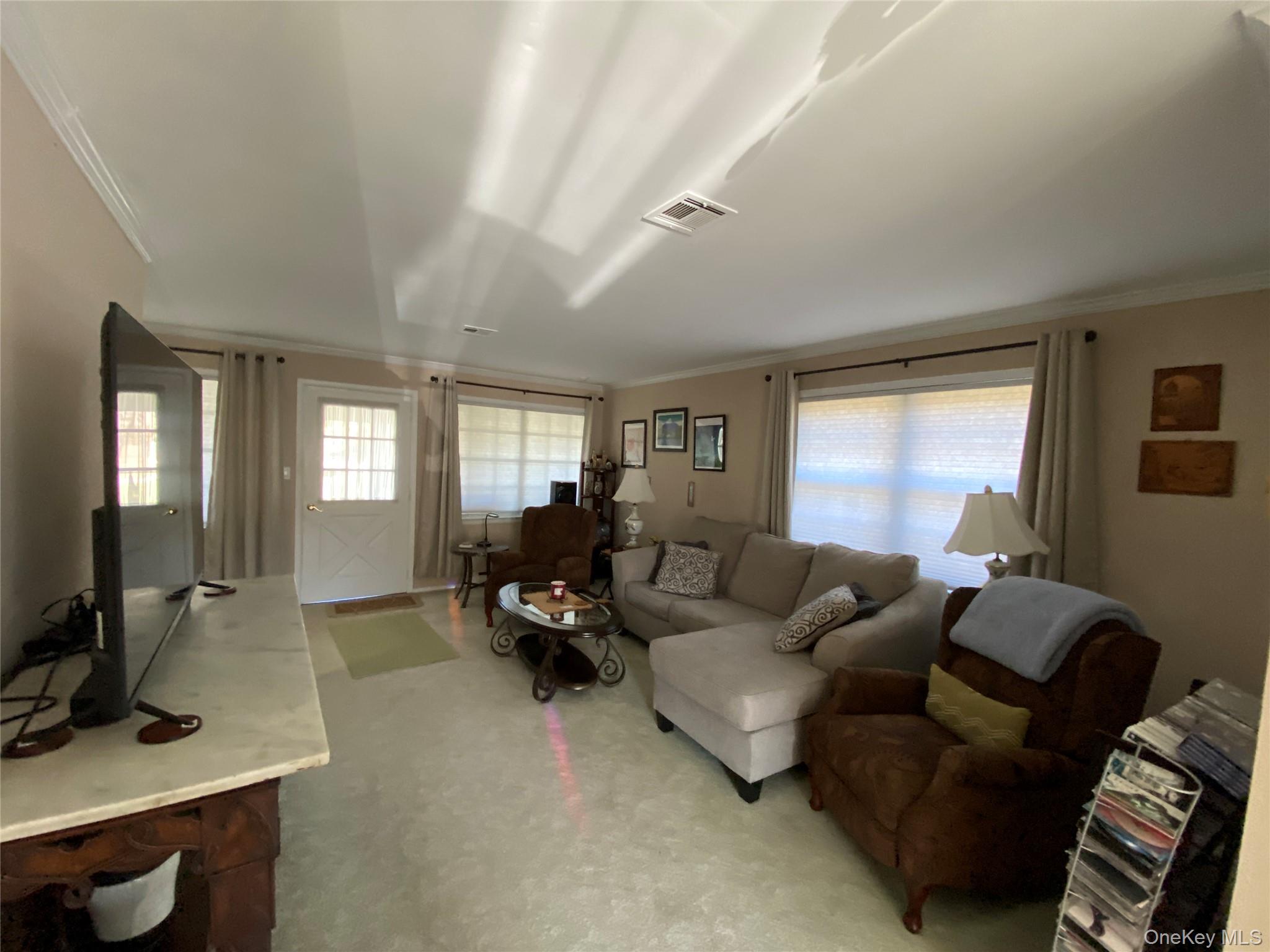 274 Berwick Court, Unit A Ridge, NY 11961 - Photo 19 of 26 Carpeted living room featuring plenty of natural light and ornamental molding