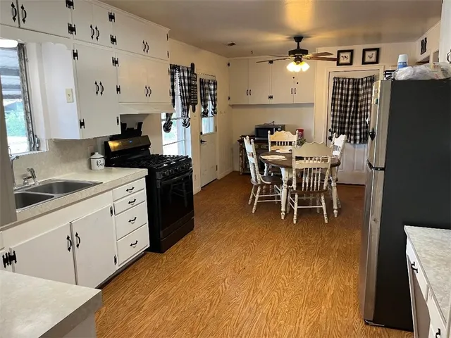 a kitchen with stainless steel appliances kitchen island granite countertop a table chairs sink and cabinets