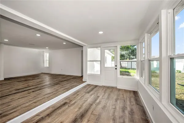 a view of an empty room with wooden floor and a window