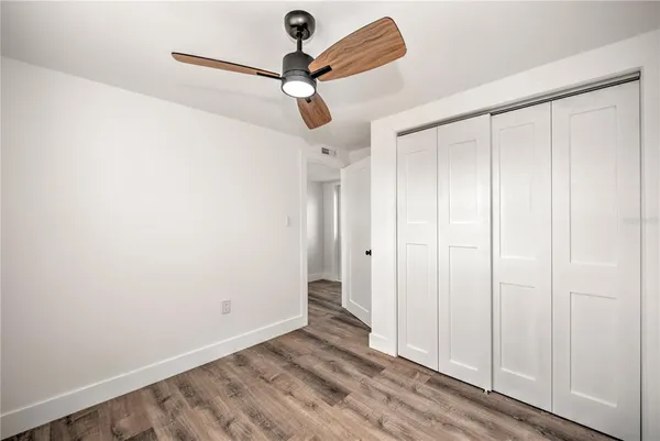 a view of empty room with wooden floor and fan