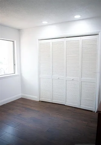 an empty room with wooden floor and closet area
