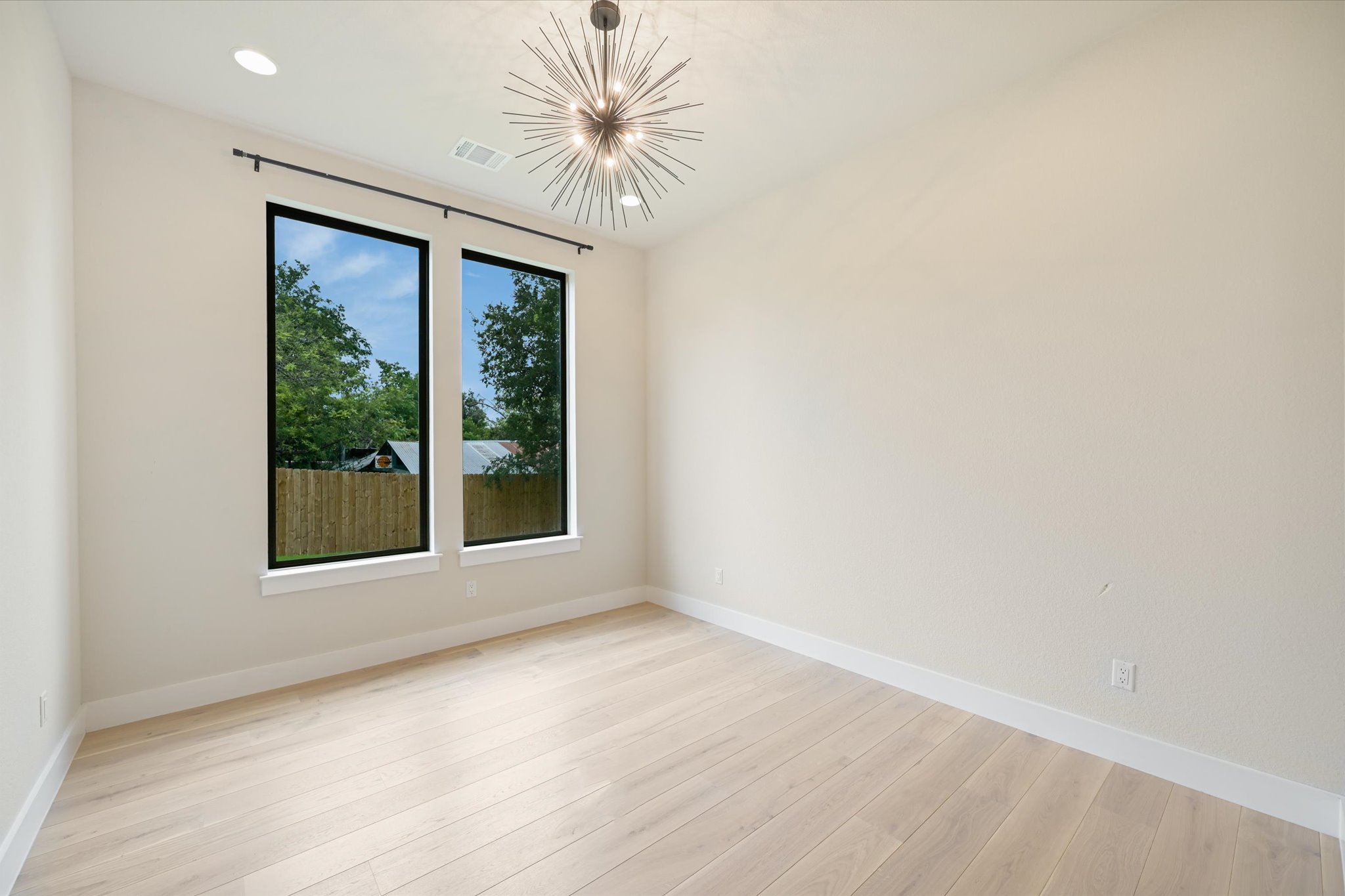 913 Presa Arriba Road Austin, TX 78733 - Photo 13 of 30 A chic sputnik light fixture illuminates light wood flooring, creating a modern and airy space.