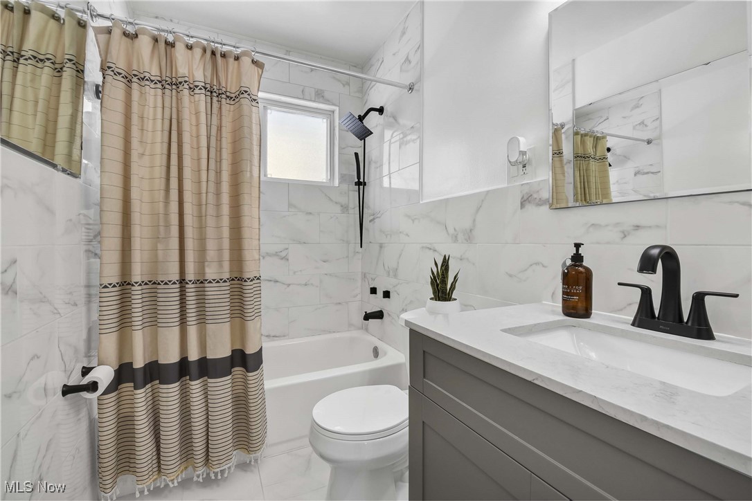 9999 Reichert Road Parma, OH 44130 - Photo 21 of 44 Bathroom with shower / bathtub combination with curtain, tile walls, vanity, and light marble finish flooring
