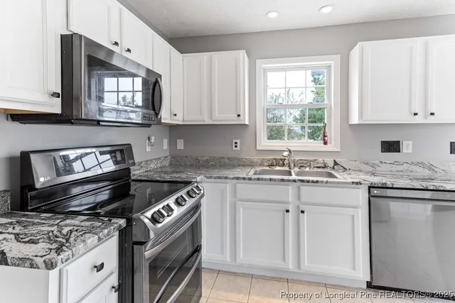 a kitchen with granite countertop a stove sink and cabinets