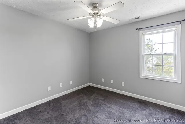 an empty room with a window and a chandelier fan