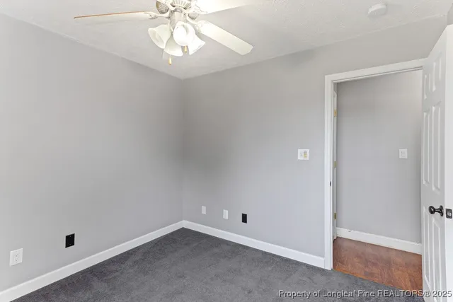 an empty room with a chandelier fan and closet