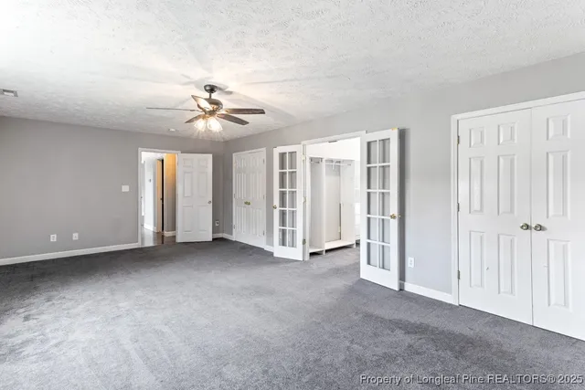 a house that is sitting in the grass with large trees and plants
