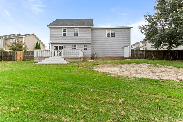 a view of a backyard with large trees and wooden fence