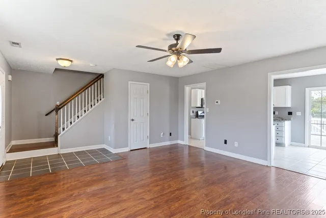 a view of an empty room with wooden floor and a ceiling fan