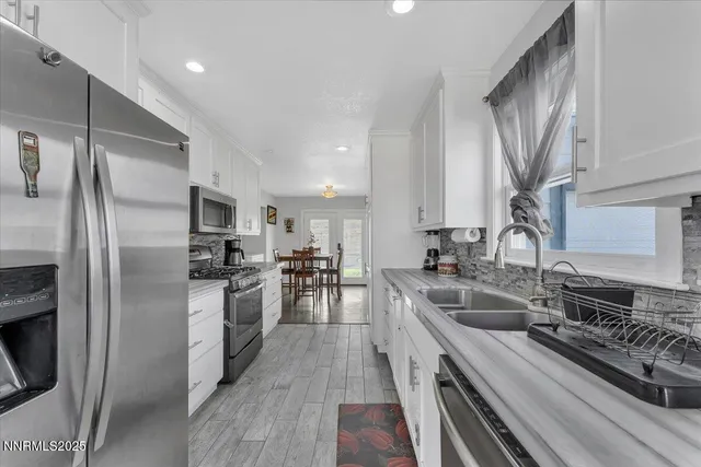 a kitchen with a refrigerator a sink a stove top oven and chairs