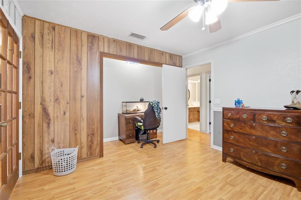 1320 Cheyenne Road Lewisville, TX 75077 - Photo 21 of 27 Wood paneling accent wall, wood-finish flooring, ceiling fan, and white trim