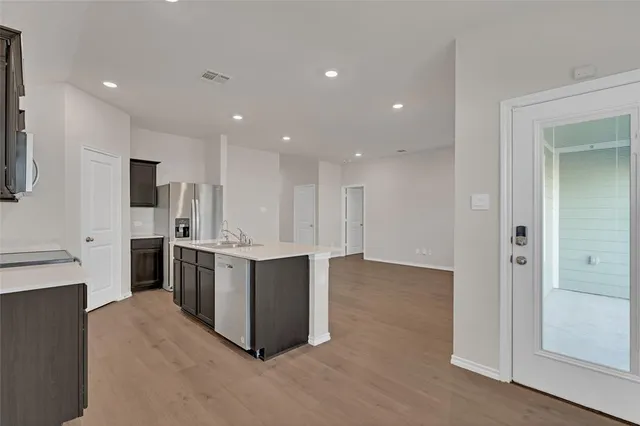 a kitchen with stainless steel appliances kitchen island granite countertop a refrigerator and a sink