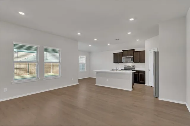 a view of kitchen with kitchen island stainless steel appliances wooden floor and window