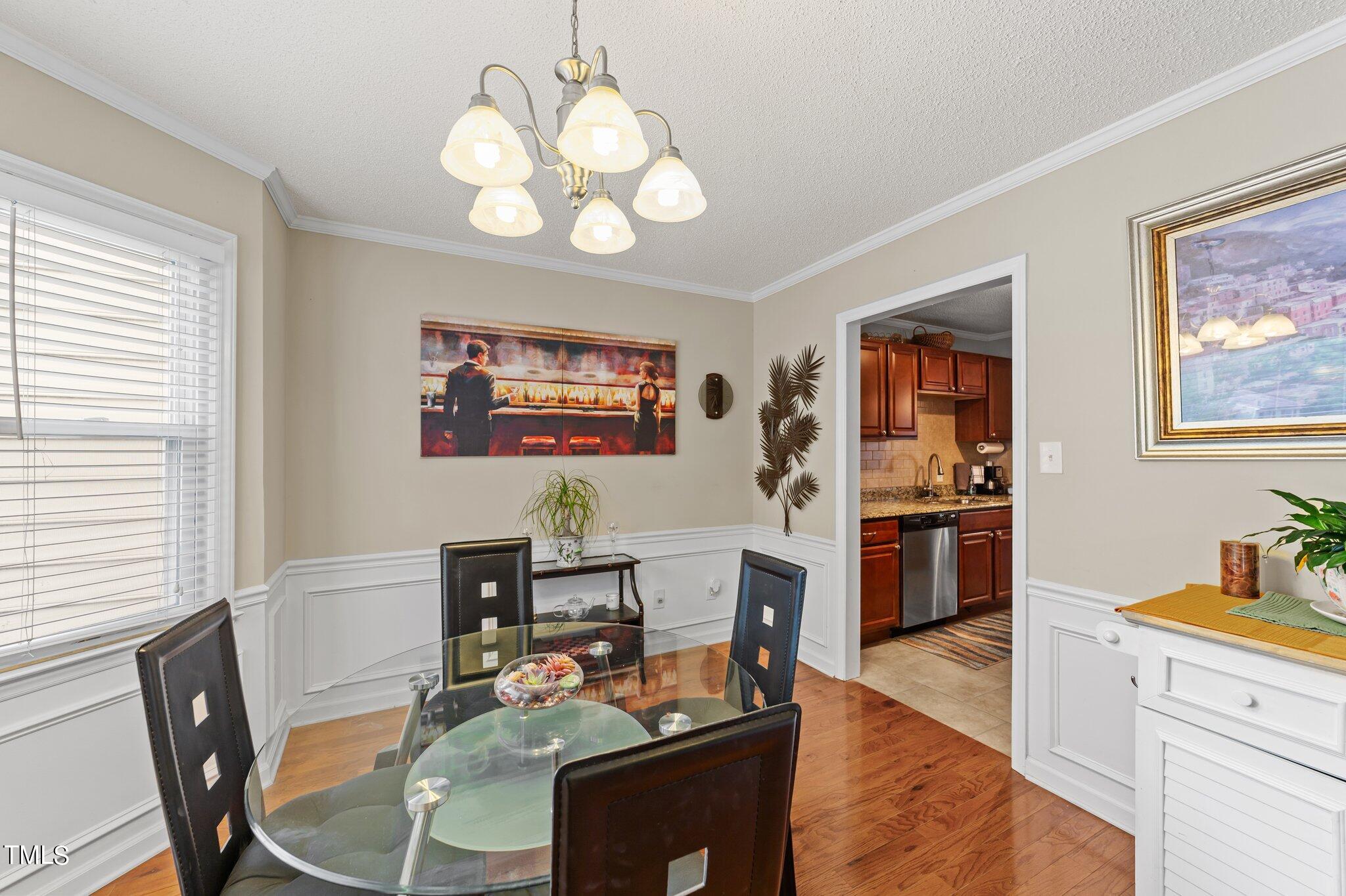 4600 Jacqueline Lane Raleigh, NC 27616 - Photo 4 of 34 a dining room with wooden floor a chandelier a glass table and chairs
