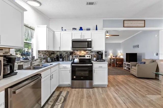 a kitchen with stainless steel appliances a stove top oven a sink dishwasher and a fireplace with wooden floor