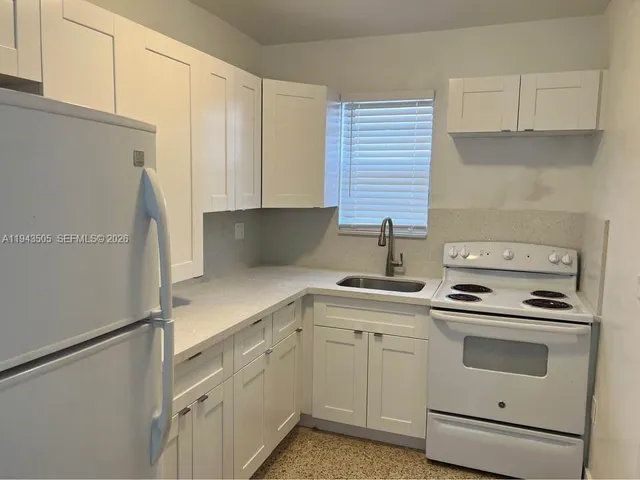 a kitchen with white cabinets and white appliances