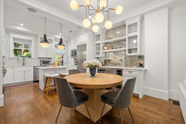 a dining room with wooden floor a chandelier fan a wooden table and chairs
