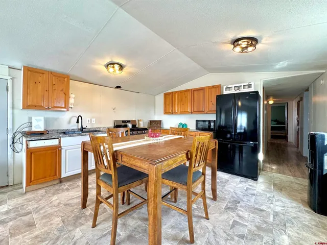 a kitchen with a dining table chairs and refrigerator