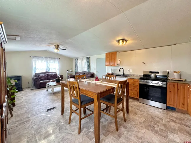 a kitchen with stainless steel appliances kitchen island granite countertop a table chairs sink and cabinets