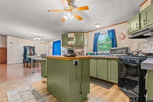 a kitchen with stainless steel appliances granite countertop a refrigerator a sink a stove and a dining table with wooden floor