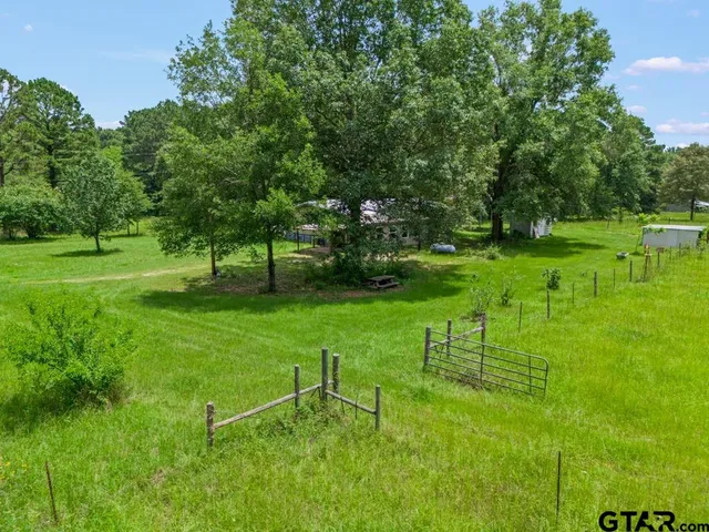 an aerial view of residential house with outdoor space and trees all around