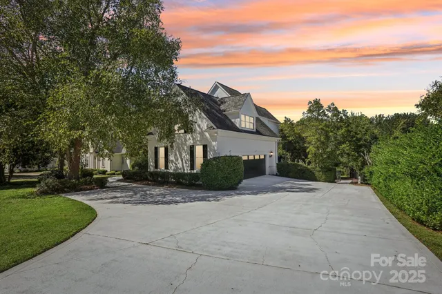 a view of a house with a yard and large trees