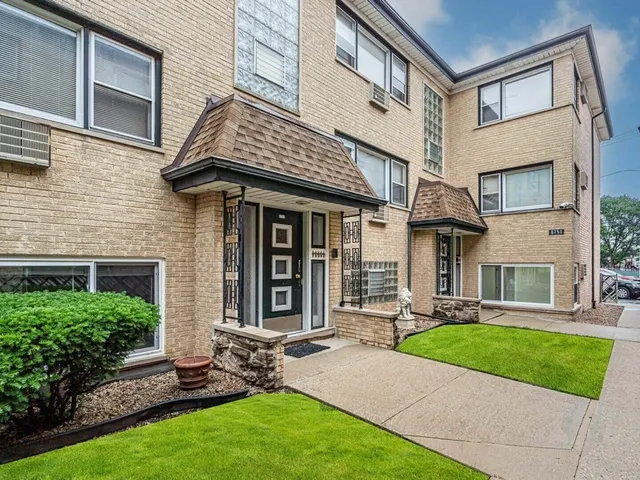 a view of a brick house with many windows and a yard