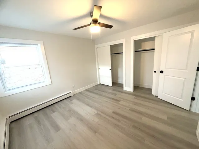 an empty room with wooden floor cabinet and windows