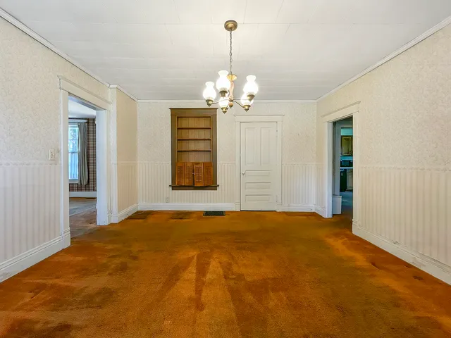 a view of a livingroom with a chandelier fan and windows