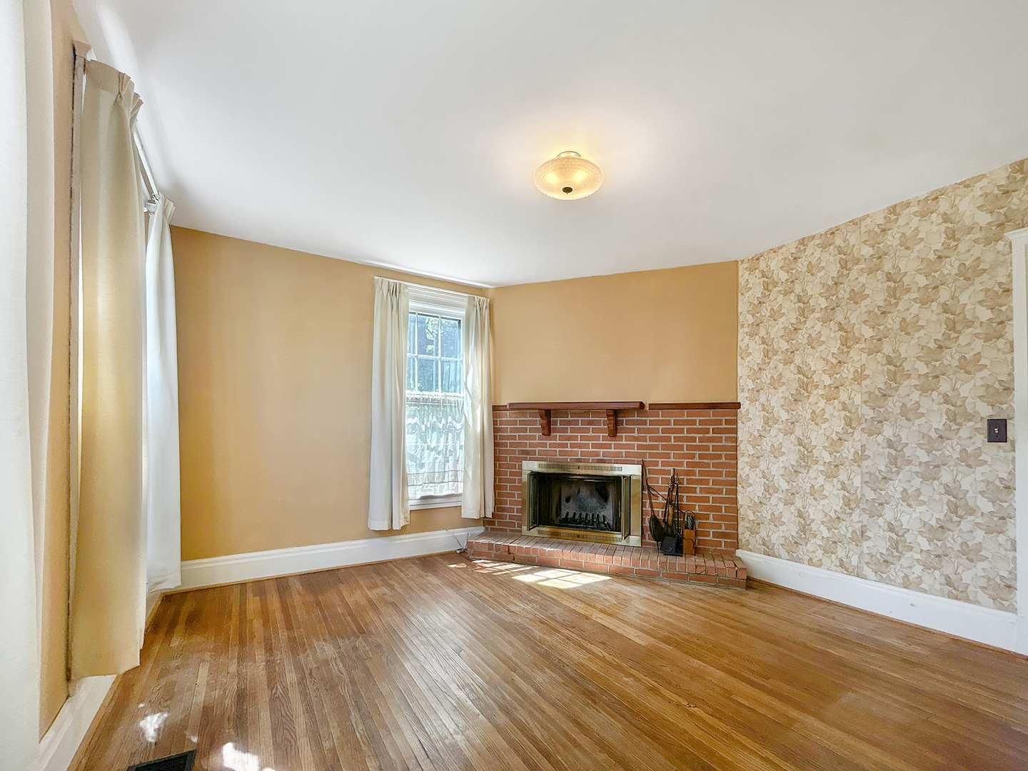 20 South Church Street Princeton, IL 61356 - Photo 4 of 17 an empty room with wooden floor a fireplace and a window