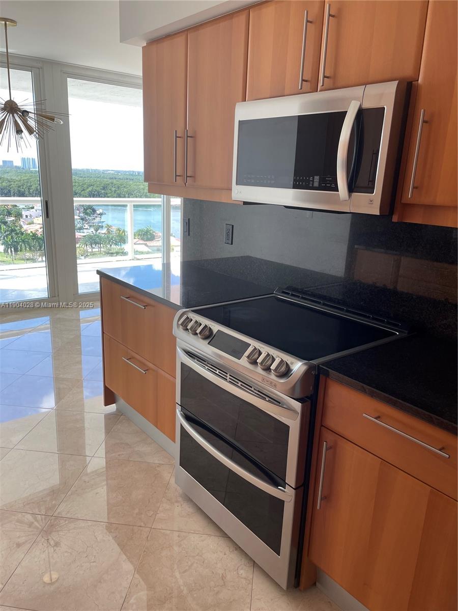 16500 Collins Avenue, Unit 1455 Sunny Isles Beach, FL 33160 - Photo 11 of 35 a kitchen with wooden cabinets and a stove top oven
