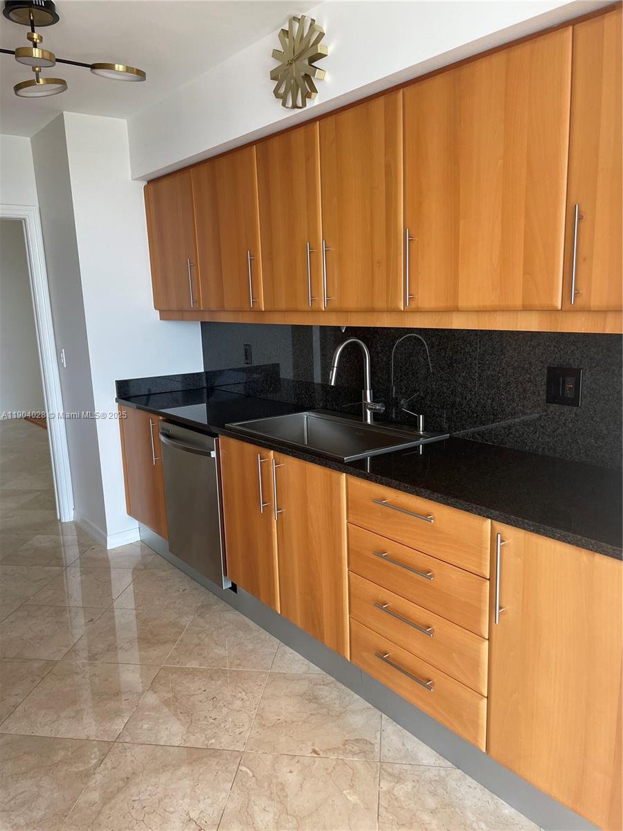 16500 Collins Avenue, Unit 1455 Sunny Isles Beach, FL 33160 - Photo 12 of 35 a kitchen with granite countertop wooden cabinets a sink and dishwasher
