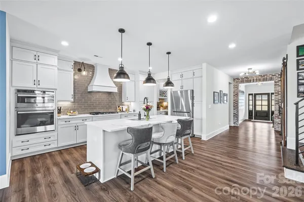 a kitchen with stainless steel appliances kitchen island granite countertop a wooden floor and white cabinets