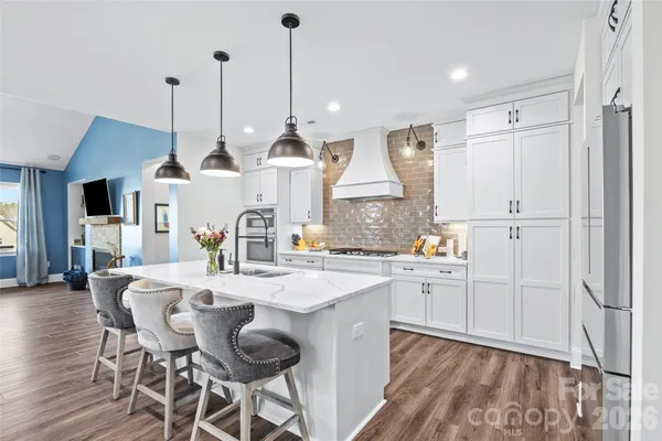 a kitchen with stainless steel appliances kitchen island granite countertop a stove a sink and a refrigerator